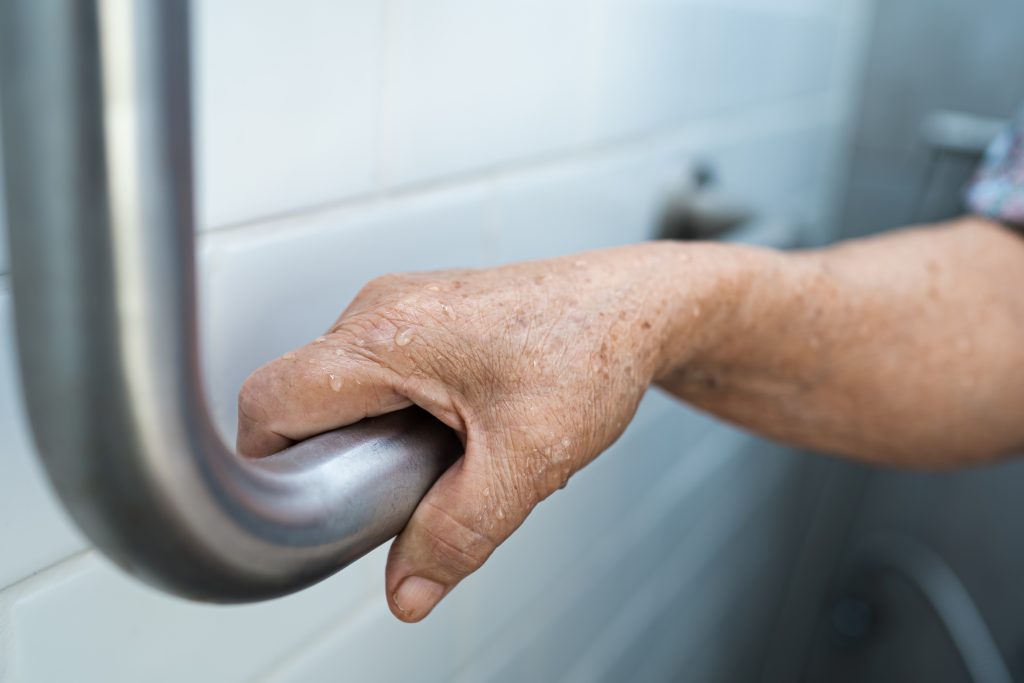 Senior or elderly adult using grab bar for bathroom safety